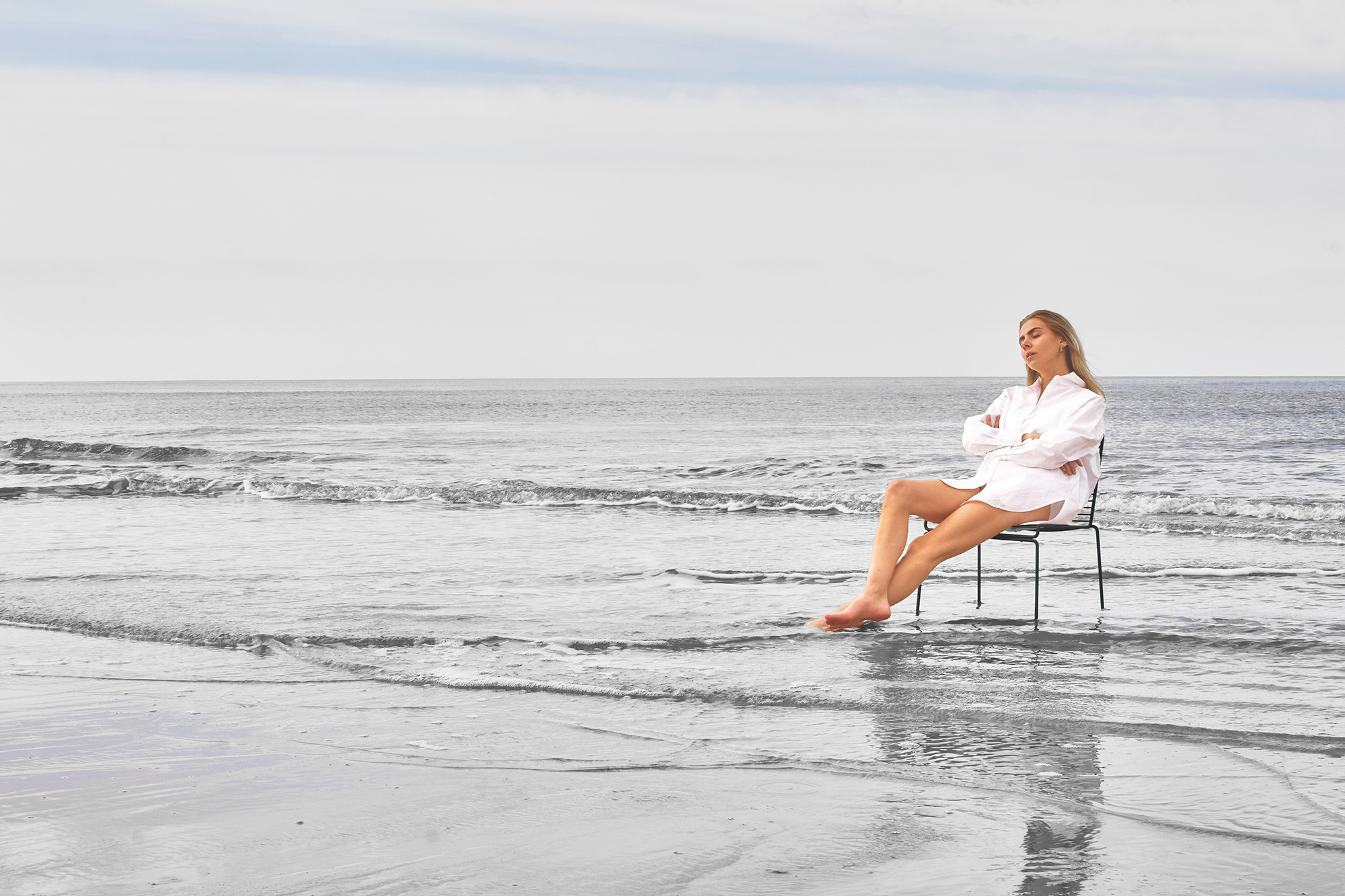 Frau mit weißem Hemd im Meer sitzend