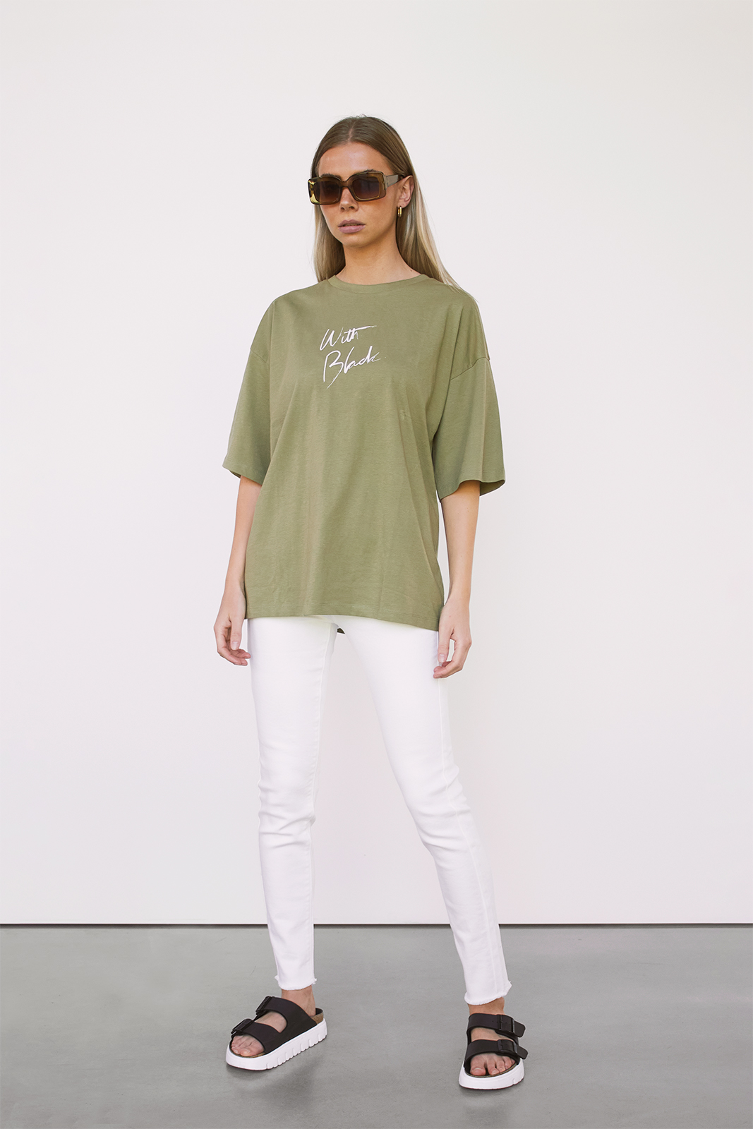woman is wearing white jeans and a green tee